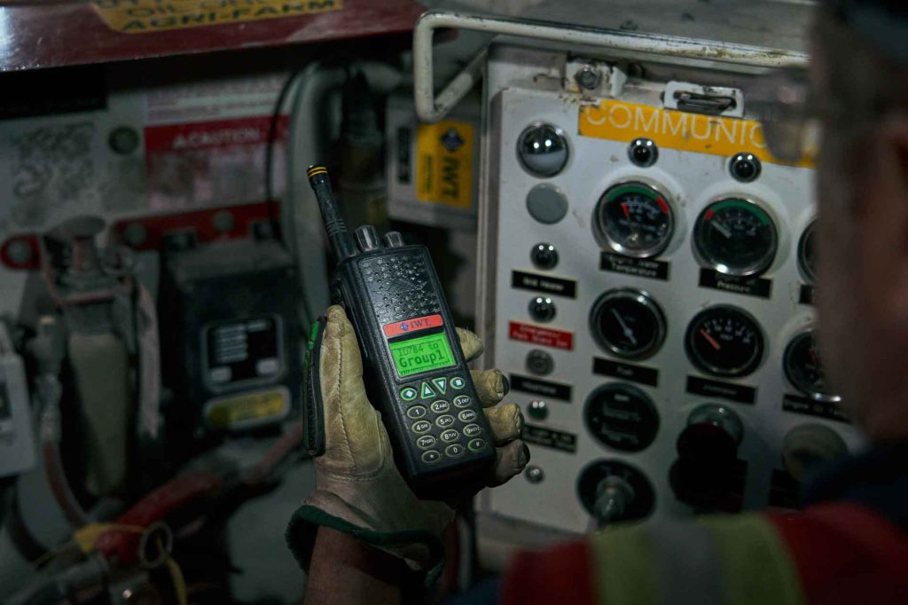 miner holds IWT radio in front of equipment