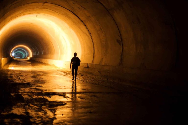 Man walking through tunnel with amber lights