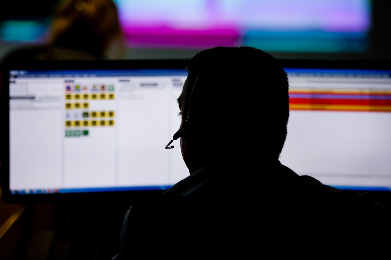 Male 911 operator in front of dispatch screens