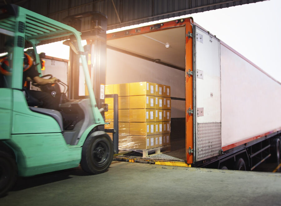 forklift delivering load onto a tractor trailer on loading dock