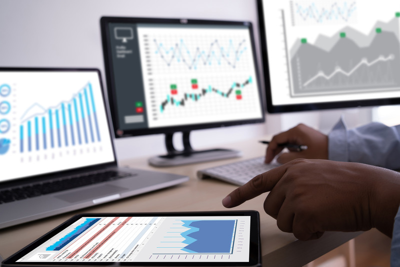 monitors on desk showing graphs