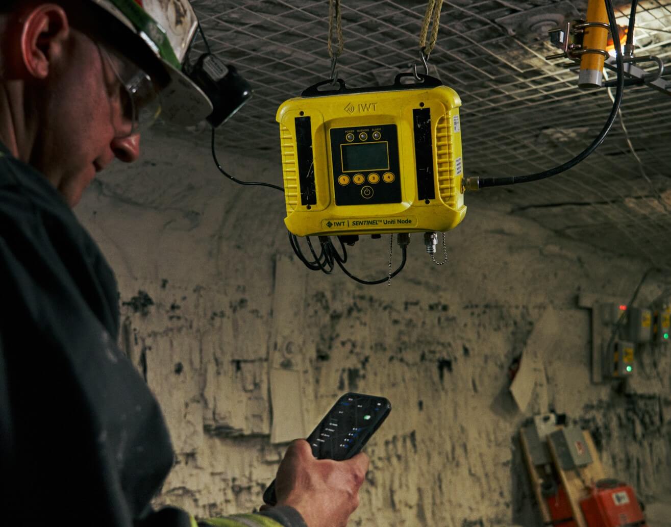 Miner checks his smartphone with Uniti device in background
